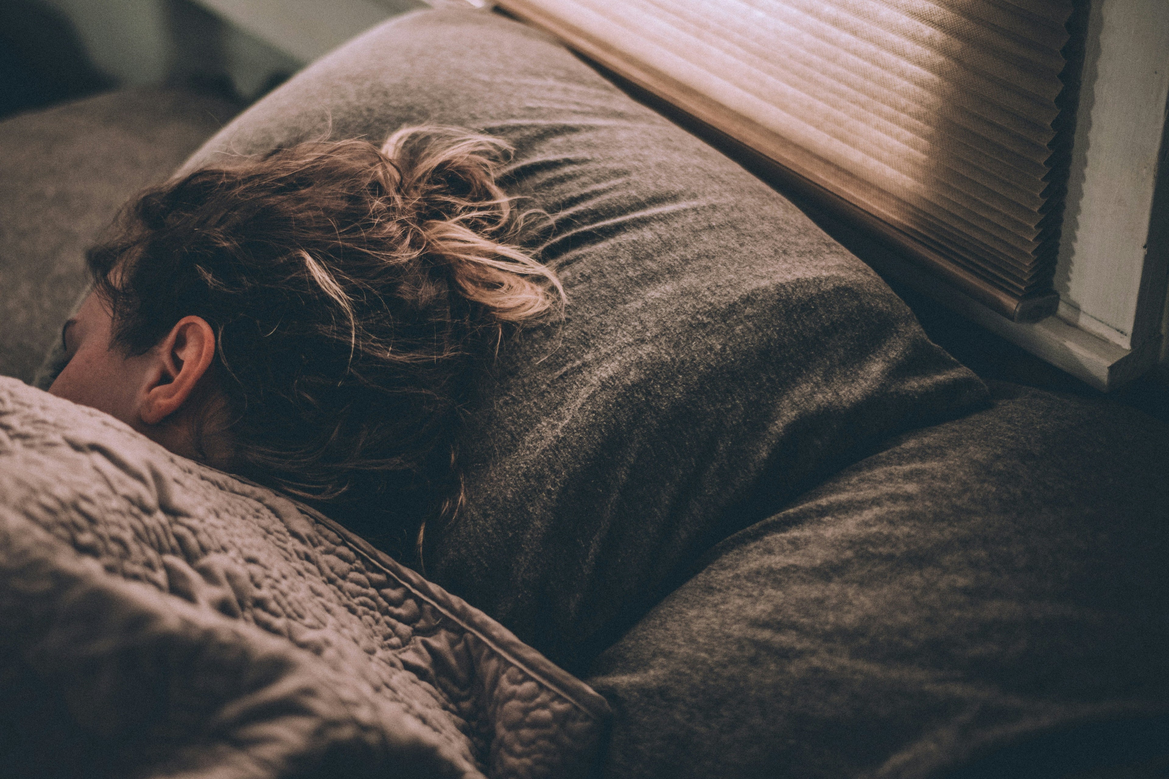 Woman sleeping on a bed with black sheets, messy black hair.