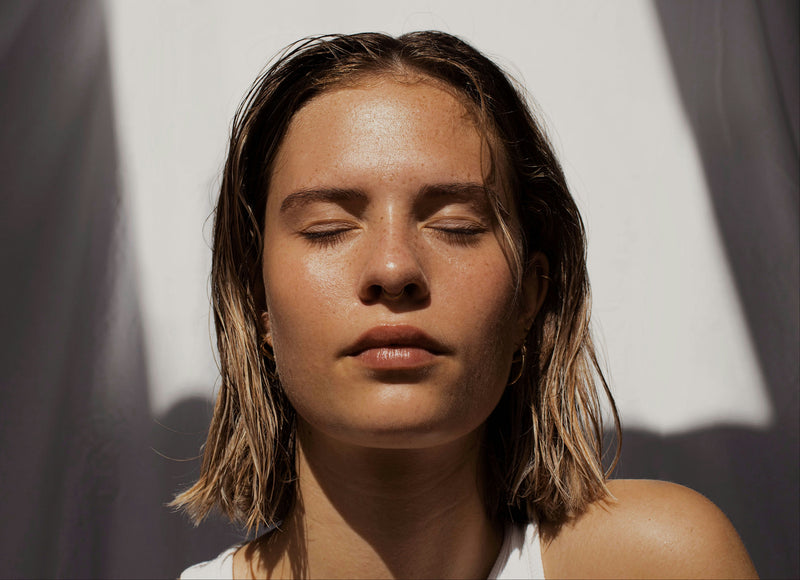 Woman with closed eyes against a white and gray background